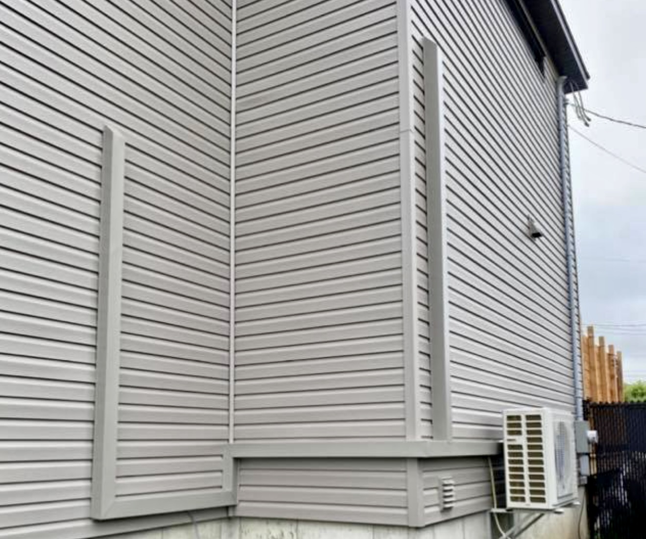Habillage d'aluminium gris sur gris sur tuyaux de thermopompe, façade arrière résidentielle à Québec